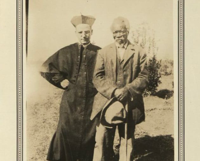 Diocesan priest standing with a previously enslaved unknown man